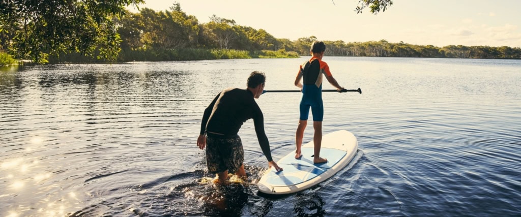 Man en jongen op sub-board op het water